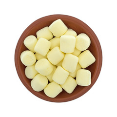 Top view of yellow miniature marshmallows in a small bowl isolated on a white background.