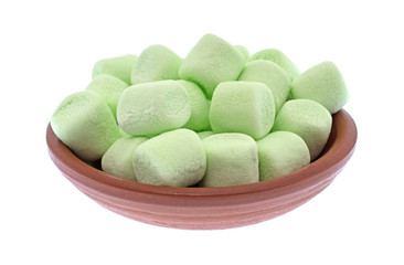 Green miniature marshmallows in a small bowl isolated on a white background.
