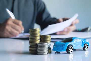 Men are Saint documents about cars  with  some coins calculator and car toy on desk