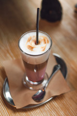 Glass of latte cappuccino coffee on wooden vintage table. Pink matcha foam in cappuccino. Stylish toning, place for text.