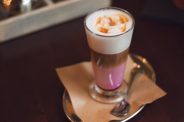 Glass of latte cappuccino coffee on wooden vintage table. Pink matcha foam in cappuccino. Stylish...