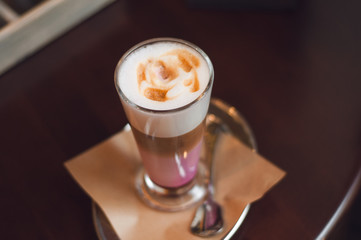 Glass of latte cappuccino coffee on wooden vintage table. Pink matcha foam in cappuccino. Stylish toning, place for text.
