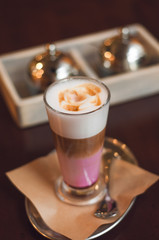 Glass of latte cappuccino coffee on wooden vintage table. Pink matcha foam in cappuccino. Stylish toning, place for text.