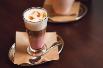 Glass of latte cappuccino coffee on wooden vintage table. Pink matcha foam in cappuccino. Stylish...