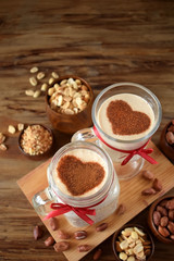 Milkshake decorated with cinnamon heart in glass vessels. Top view. Peanuts are around