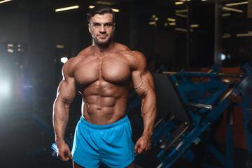 Naklejka na ściany i meble Handsome model muscle man abs workout in gym