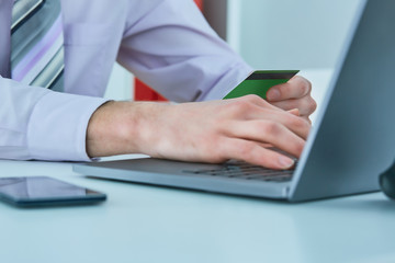 Man's hands holding a credit card and using smart phone for online shopping. Online payment