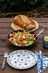Lettuce and tomatoes salad on wooden table. In the garden. 
