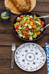 Lettuce and tomatoes salad on wooden table. In the garden. 
