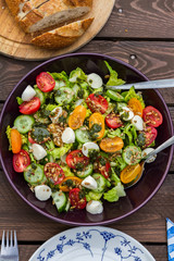 Lettuce and tomatoes salad on wooden table. In the garden. 
