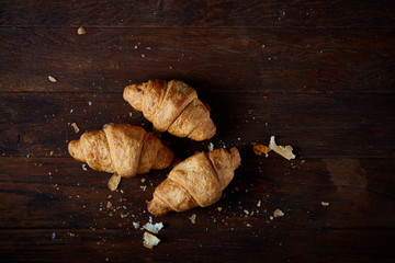 Tasty buttery croissants on an old wooden table, close-up, selective focus, shallow depth of field.