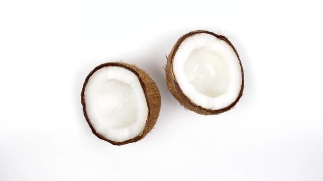 Top view of two ripe tropical coconut halves with yummy white pulp rotating on white isolated background. Healthy fresh tropical fruits. Loopable seamless cocos rotating