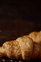Tasty buttery croissants on an old wooden table, close-up, selective focus, shallow depth of field.