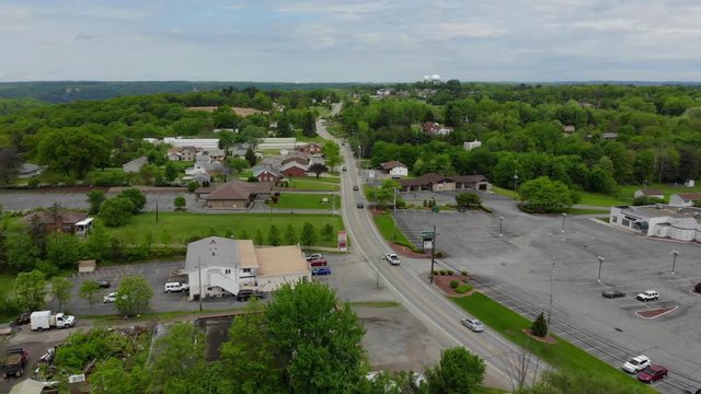 A daytime aerial establishing shot of a typical street and businesses district in Pennsylvania. Pittsburgh suburbs. Forward moving.  	