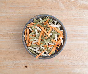 Top view of vegetable noodles in an old stoneware bowl on a table.