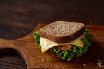 Tasty and fresh sandwiches on cutting board over a dark wooden background, close-up