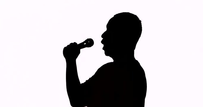 Silhouette of a male singer singing a song with a microphone and classical gesture in the studio, isolated on white background. Shot in 4k resolution