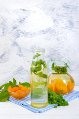 Summer cold drinks. Delicious refreshing drink with apricot and mint in glasses on a white wooden background. Compote of fruits.