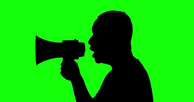 Silhouette of unidentified man talking with a megaphone in the studio, shot in 4k resolution with green screen background