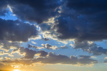 the sun is located low above the horizon illuminates its rays clouds against the blue sky, creating a contrasting image using natural light and shadows