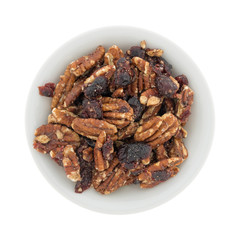 Top view of sugar glazed pecans with dried cranberries in a white bowl.