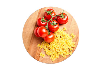 Heap farfalle italian pasta and Fresh Red ripe tomatoes on a green branch laying on wooden beech board. Isolated on white background
