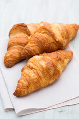 Tasty buttery croissants on old wooden table.