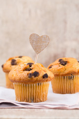 Homemade chocolate muffins with heart, vintage background.