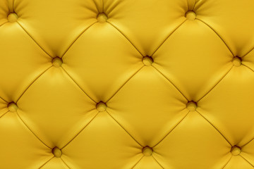 Background of leather yellow sofa, stitched buttons.