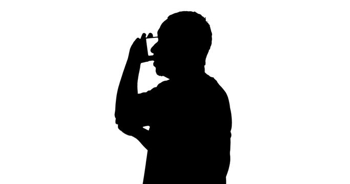 Silhouette of man talking on a mobile phone while standing in the studio, isolated on white background. Shot in 4k resolution