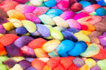 Bunt gefärbte und geflochtene Zöpfe aus Strickwolle nebeneinander aufgereiht