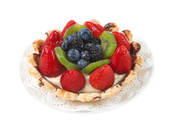 Fresh summer fruit tart with strawberries, kiwi, blueberries, boysenberries on a white doily on plate isolated on white background.