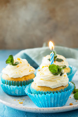 Orange Birthday cupcake with buttercream icing and candle on a blue a stone or slate background. Copy space.