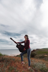 girl with a guitar on a cliff near the ocean