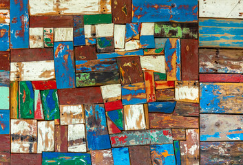 Surface of old and worn out wooden panels painted in several colours with the apaint peeling off