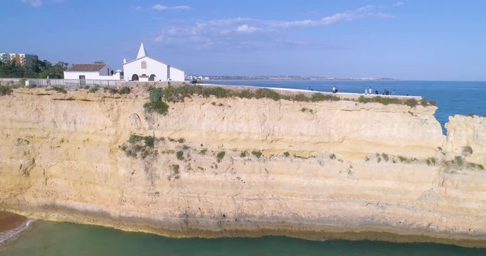 Aerial rocky famous seascape cape and Senhora da Rocha church on top of cliff, in Algarve south coast.