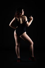 Obraz premium Beautiful sexy woman in bodysuit posing on black background, low key studio shot
