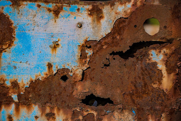 Old, rusted metal with holes in it and some remaining blue paint