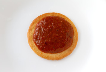 Fototapeta na wymiar Roasted red bell pepper spread on a cracker on a white plate.