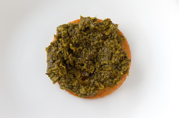Chopped parsley spread on a cracker atop a white plate.