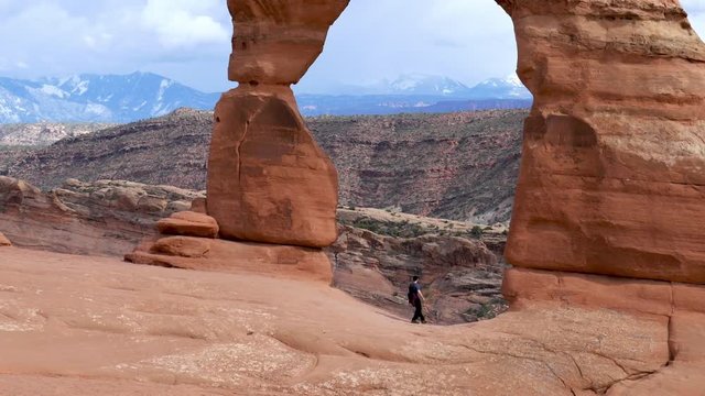 A man posing for a photo on the background of Delicate Arch, Arches National Park, Utah, USA