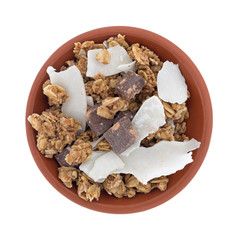Top view of a bowl filled with organic granola with chocolate and coconut flakes isolated on a white background.