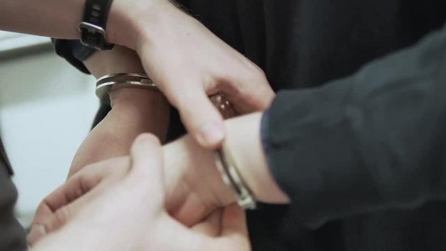 Criminal gets handcuffed by police while booked in jail.