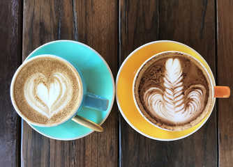 Two delicious aromatic americano coffee with foam in the shape of heart in a vintage blue cup and spoon on old wooden table, top view