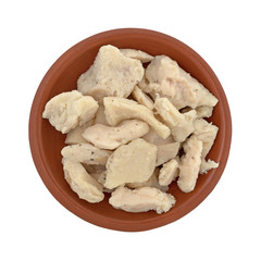 Top view of chicken breast chunks in a small bowl isolated on a white background.