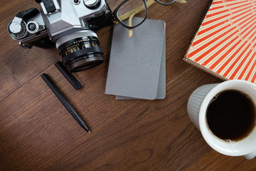 Camera, Coffee and Notebook on a Wooden Table