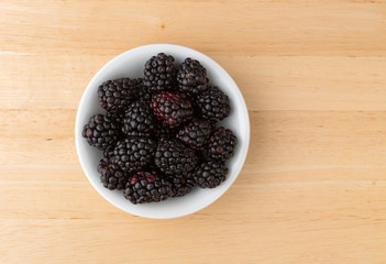 Blackberries in a bowl on a wood table