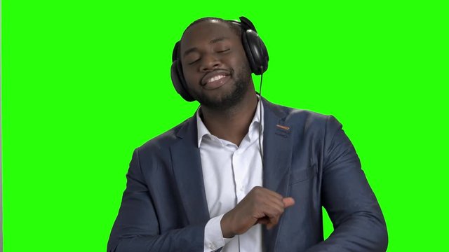 Stylish businessman listening to music in headphones. Portrait of cheerful afro american entrepreneur singing and dancing on Alpha Channel background.