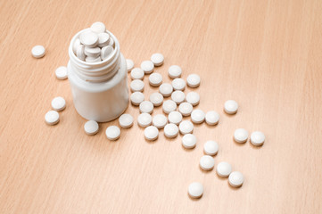 Fototapeta na wymiar Pills and plastic bottle on the wooden table.