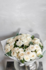 white spray roses. Bouquet of beautiful flowers on wooden table. Floristry concept. the work of the florist at a flower shop. Vertical photo